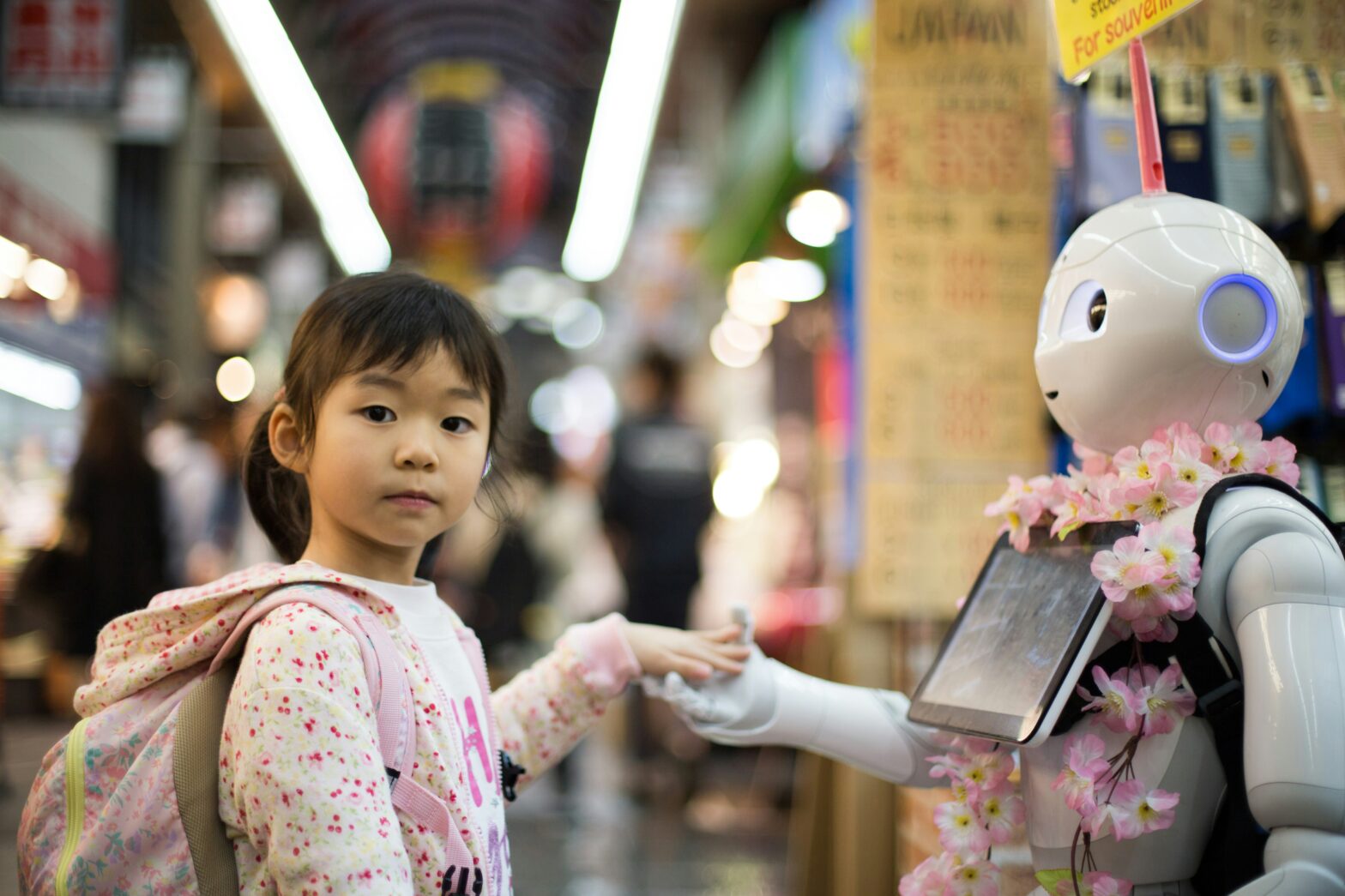 A little girl takes a robot's hand. Image courtesy of Andy Kelly on Unsplash