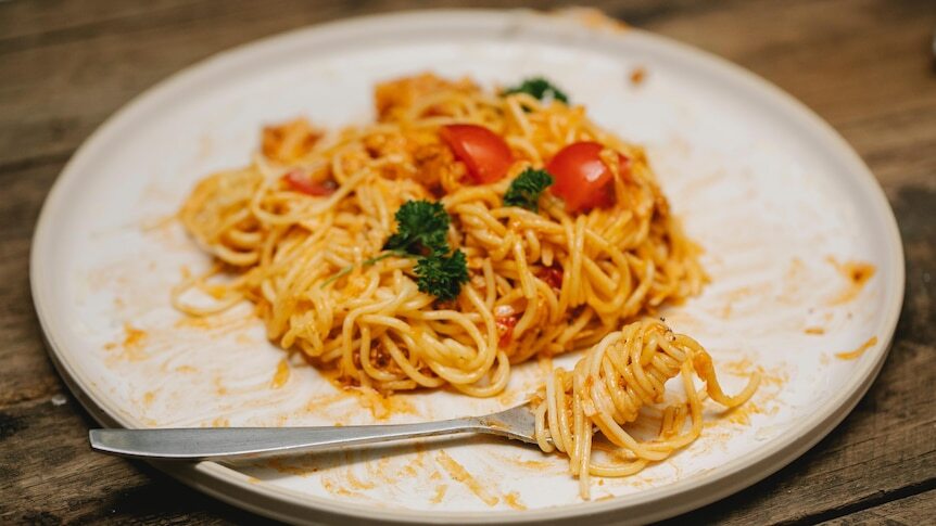 Pasta on a dish with sauce as the focus for debate on how to cook pasta and save energy