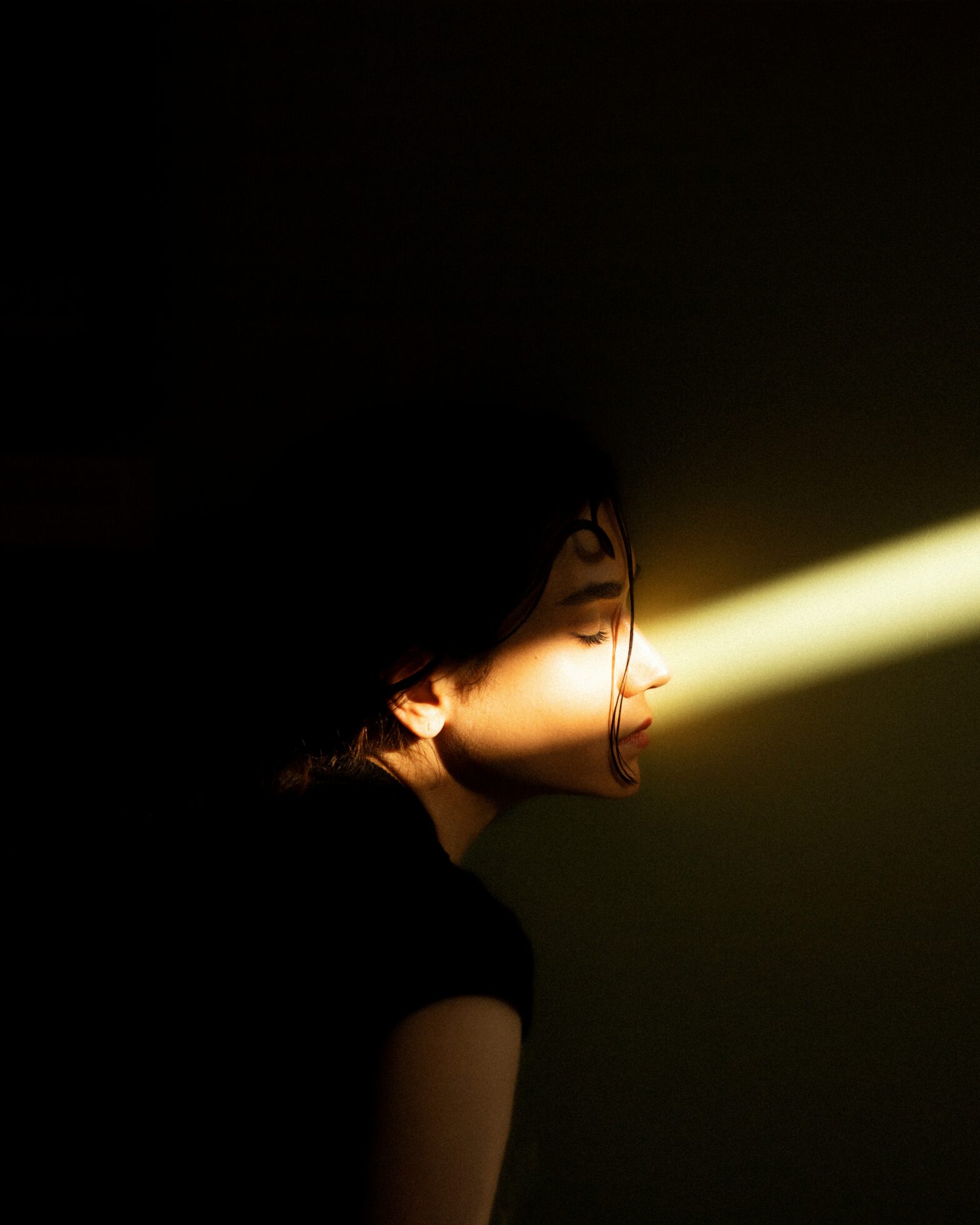 Woman standing in a dark room with a shaft of light illuminating her eyes - Aytam Zaker on https://unsplash.com/photos/a-woman-standing-in-a-dark-room-with-a-light-coming-through-her-eyes-EcdtLQW8JiI Unsplash