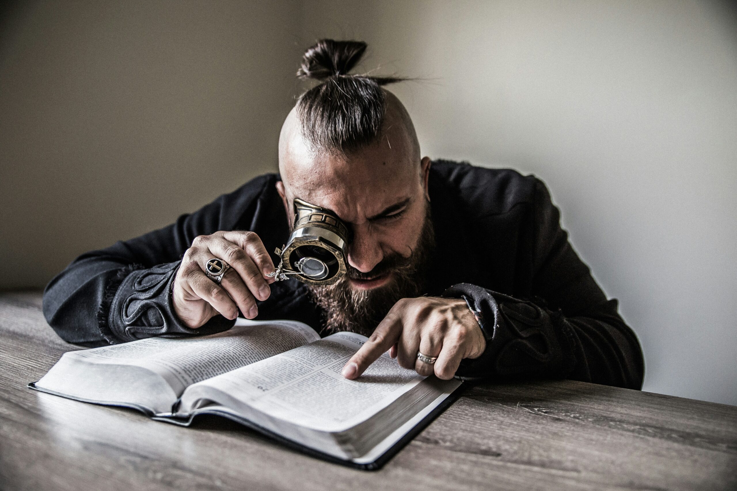 Photo by Nathan Bingle man holding reading magnifying glass reading a book on brown wooden table Unsplash