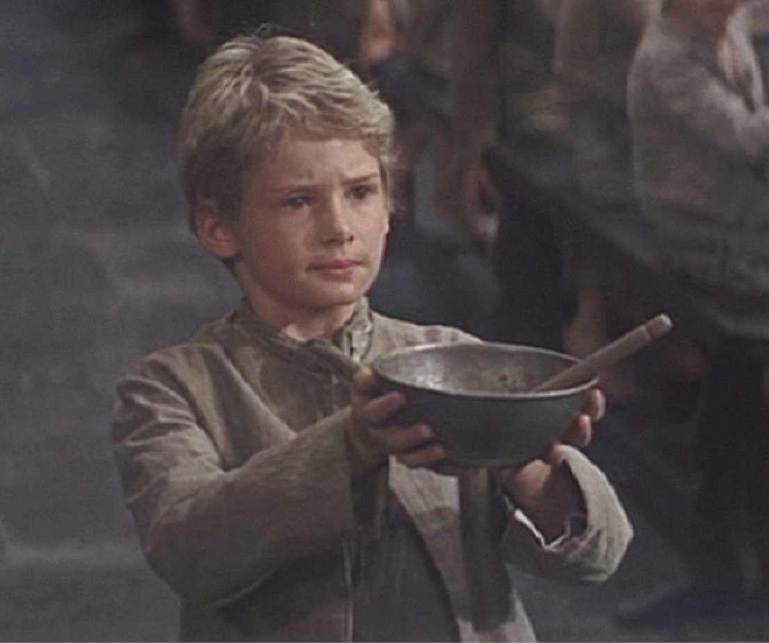 More please, asked Oliver, an orphan in rags with an empty bowl. A still from Oliver Twist